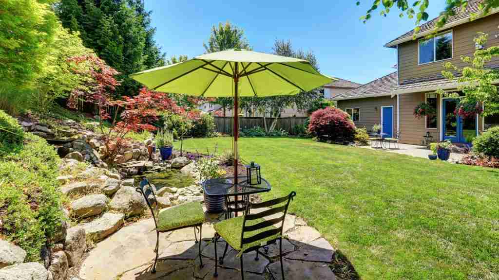 Backyard remodeling featuring a patio seating area, umbrella, and landscaped garden
