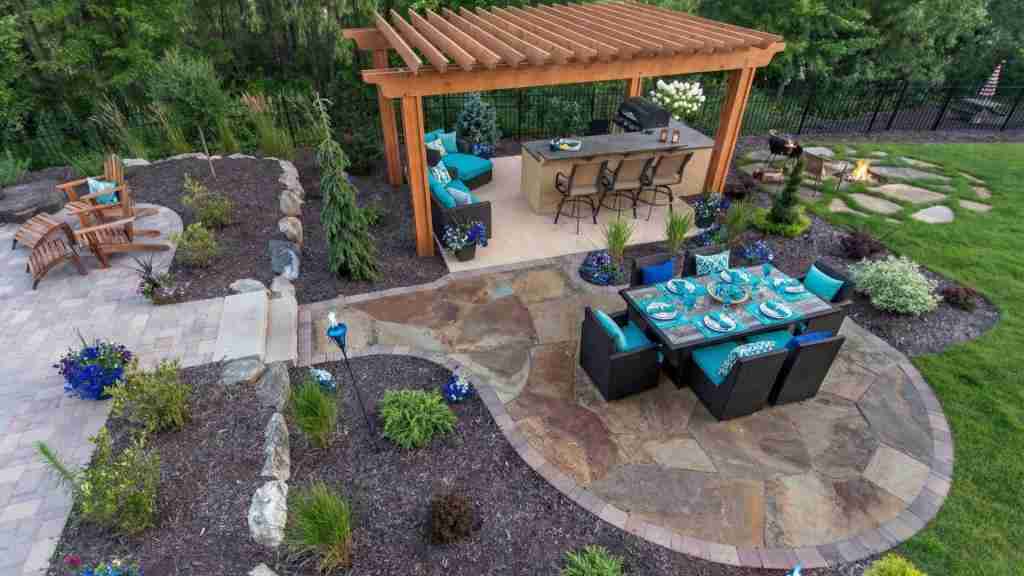 A well-landscaped outdoor space with a modern patio, dining area, and pergola